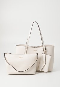 Ensemble de sacs à main en cuir beige comprenant un grand tote, un moyen étui avec une bandoulière et un petit portefeuille. Fini texturé et accents en logo doré.