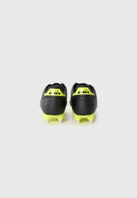 Pair of black and neon yellow Diadora football boots viewed from the back on a plain white background.