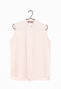 Blusa senza maniche di colore rosa chiaro con collo alto, piega centrale e piccoli dettagli con bottoni al collo. Tessuto morbido e liscio.