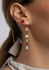 Goldene Tropfohrringe mit verschiedenen bunten Edelsteinen, darunter rot, grün und pink, arrangiert in einem linearen Design mit kontrastierenden Formen.