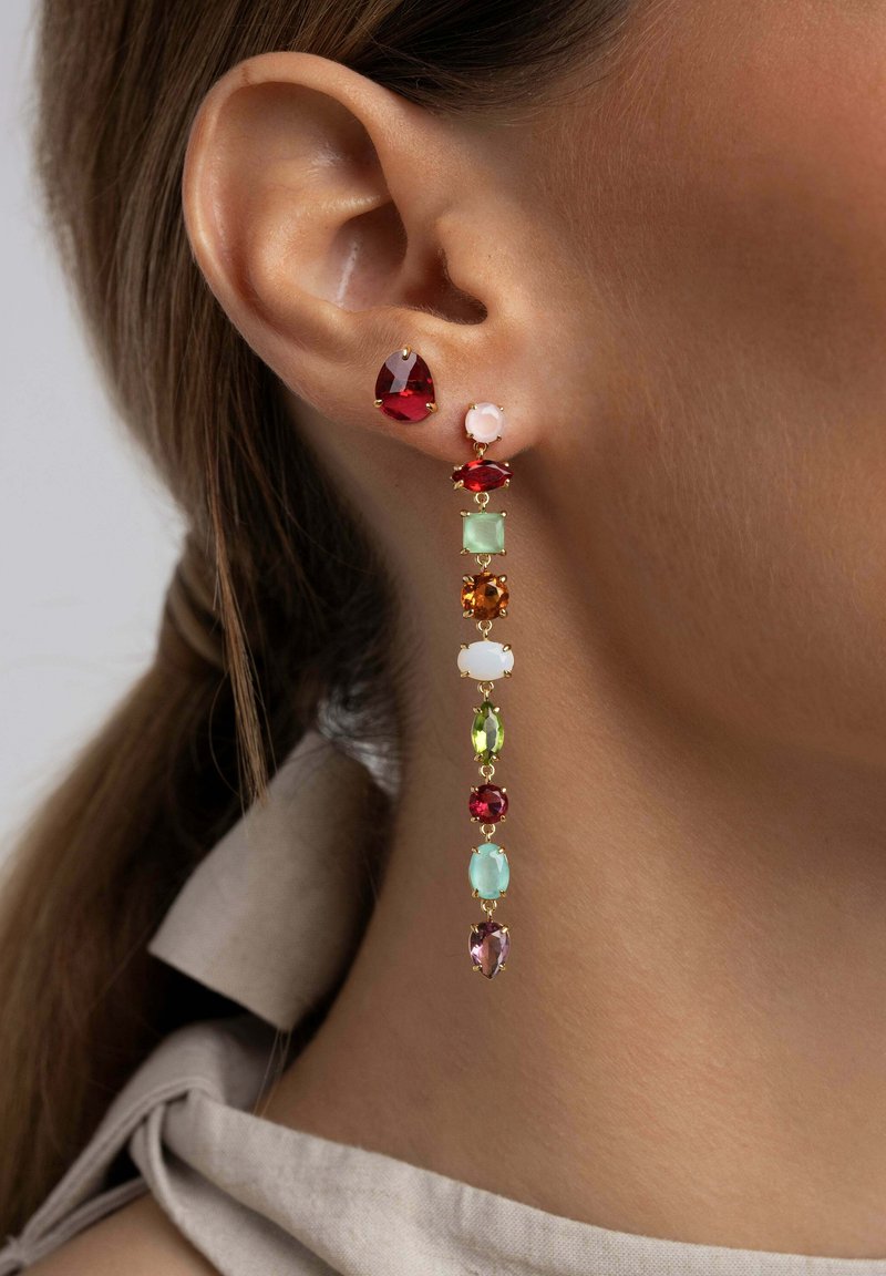 Goldene Tropfohrringe mit verschiedenen bunten Edelsteinen, darunter rot, grün und pink, arrangiert in einem linearen Design mit kontrastierenden Formen.