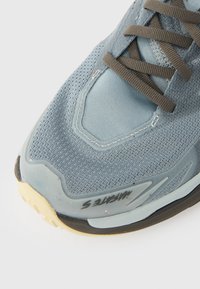 Hellblauer Sneaker mit strukturiertem Mesh-Obermaterial, grauen Schnürdetails und einer Gummisohle mit sichtbarem Profil.