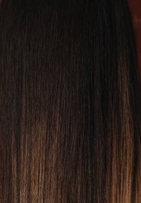 Długie, proste włosy o ciemnobrązowej bazie stopniowo przechodzące w jaśniejszy brąz na końcówkach, prezentujące gładką, błyszczącą teksturę.