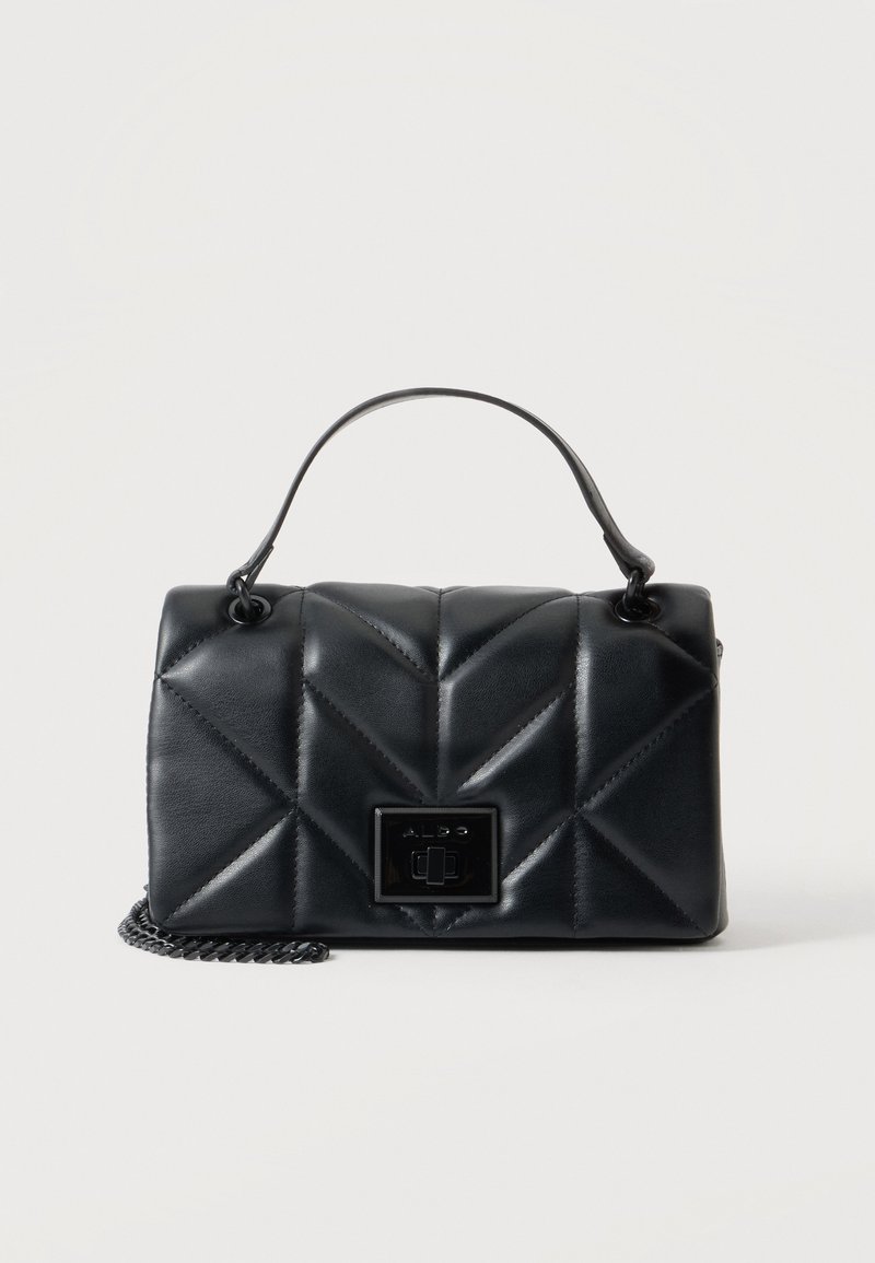 Sac à main en cuir noir matelassé avec poignée supérieure, forme rectangulaire et fermeture à clip métallique à l'avant sur une bandoulière chaîne sur fond uni.