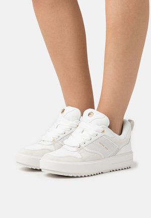 Sneaker atletici bianchi che presentano una combinazione di pelle liscia e rete testurizzata, con lacci piatti, dettagli dorati e una suola spessa.