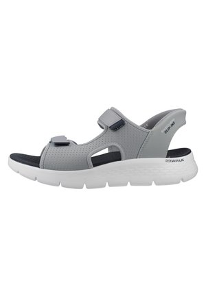 Sandalia slip-on gris de Skechers con tiras perforadas, cierres ajustables de velcro, plantilla negra contorneada y suela gruesa acolchada blanca.