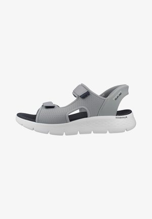 Sandalia slip-on gris de Skechers con tiras perforadas, cierres ajustables de velcro, plantilla negra contorneada y suela gruesa acolchada blanca.