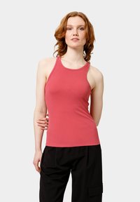 Top sin mangas rosa estriado con diseño de espalda nadadora, forma ceñida y escote amplio. Combinado con pantalones negros holgados.