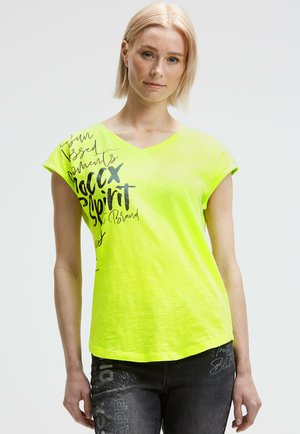 Neon yellow v-neck t-shirt with short cuffed sleeves, featuring black graphic text designs. Soft fabric with a relaxed fit.