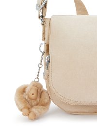 Borsa a spalla in tessuto beige con forma arrotondata, chiusura con zip e un portachiavi a forma di scimmia in pelliccia sintetica attaccato tramite una catena argentata.