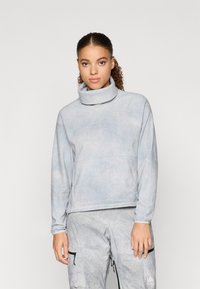 Svetlo modri pulover z visokim ovratnikom, izdelan iz mehkega materiala. Ima subtilen vzorec in majhen logo na prsih.