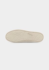 Suela de un zapato beige con patrones florales en relieve y el nombre de la marca "ALDO" visible cerca del centro.