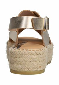 Metallische gouden sandalen met een gevlochten jute-wedgezool, met een gespstrap en een open achterontwerp, die een gladde textuur tonen.