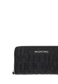 Portafoglio in pelle nera con logo "VALENTINO" in rilievo. Forma rettangolare, chiusura a zip, superficie testurizzata e dettagli in metallo color argento.