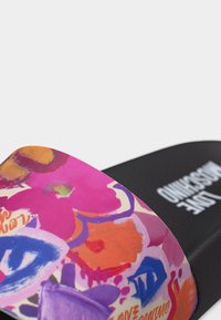 Μαύρο σανδάλι με φαρδιά λουρί που διαθέτει πολύχρωμα αφηρημένα ανθισμένα και γεωμετρικά σχέδια σε ροζ, πορτοκαλί, μοβ και μπλε.