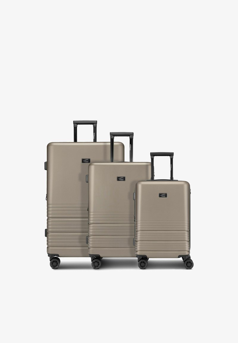 Drei beige Hartschalenkoffer in unterschiedlichen Größen mit ausgezogenen schwarzen Griffen und vier Spinner-Rädern, nebeneinander auf weißem Hintergrund angeordnet.