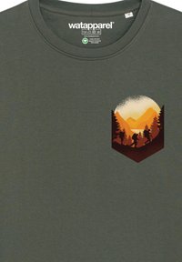 Donkergroene katoenen t-shirt met een afbeelding van wandelaars tegen een zonsondergang met oranje bergen en bomen in een hexagonaal kader.