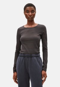 Langärmliges, dunkelgraues gestreiftes Shirt aus weichem Material mit Rundhalsausschnitt. Dazu weite marineblaue Jogginghosen mit elastischem Bund.