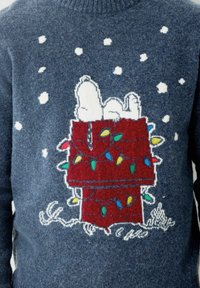 Maglione blu lavorato a maglia con un design di Snoopy su una cuccia rossa, decorata con luci colorate e circondata da fiocchi di neve bianchi.
