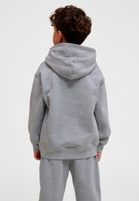Grå hoodie med stor huva och känguruficka. Gjord av ett mjukt, texturerat tyg, med ribbade muddar och fåll.