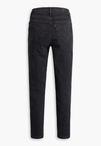 Jean en denim noir à coupe slim, avec deux poches arrière à la forme incurvée distincte et un discret détail en forme de languette rouge.