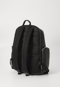 Black backpack featuring a textured surface, padded shoulder straps, dual zipper closure, and side pocket. Sturdy and practical design.