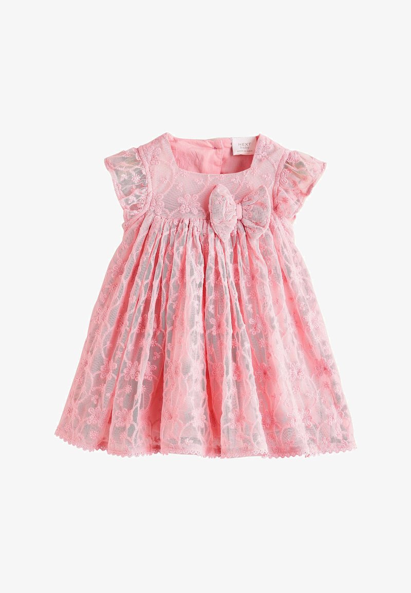 Robe bébé rose avec superposition de dentelle florale, manches courtes bouffantes, jupe froncée et un grand nœud sur le corsage devant.