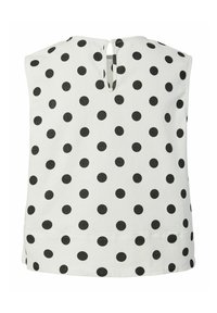 Blouse blanche sans manches à pois noirs, avec une petite ouverture en forme de goutte d'eau au dos du col.