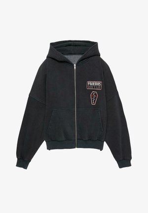 Hanorac cu fermoar de culoare neagră, fabricat dintr-un amestec de bumbac. Are o glugă spațioasă, buzunare frontale și inscripții brodate, cu texte și modele grafice.