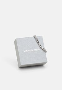 Ezüst textúrájú ékszerdoboz, ezüst lánc díszítéssel, a hátoldalán fehér betűkkel emblémázva a "MICHAEL KORS" felirattal.
