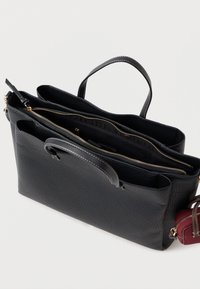 Μαύρη δερμάτινη τσάντα tote με υφή, που διαθέτει κλείσιμο με φερμουάρ στην κορυφή, εσωτερικές τσέπες και αποσπώμενη κόκκινη θήκη με φερμουάρ.