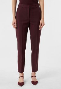 Burgundowe spodnie o dopasowanym kroju z gładką fakturą, z paskiem, fałdami z przodu oraz zwężanym nogawką. W połączeniu z szpilkami o wąskim nosku.