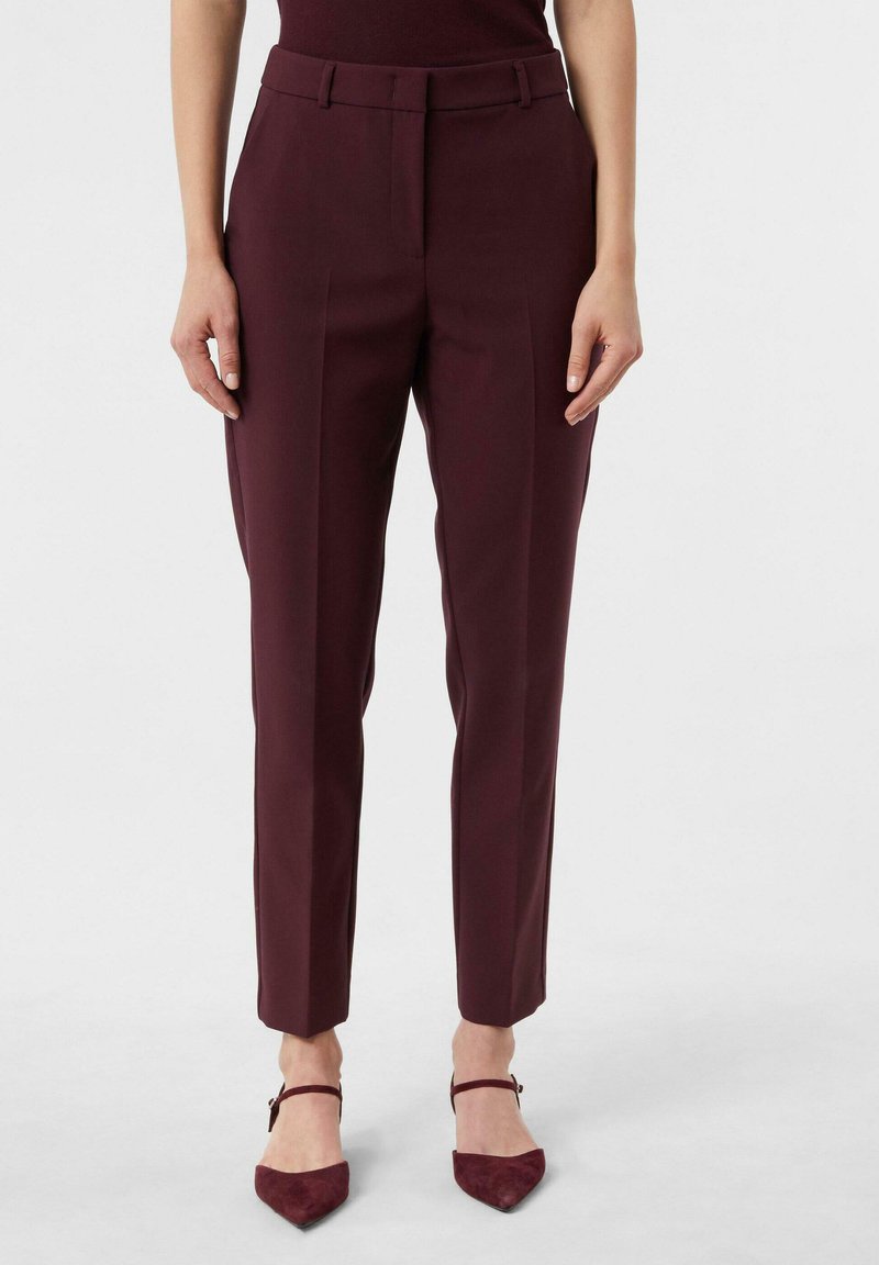Burgundowe spodnie o dopasowanym kroju z gładką fakturą, z paskiem, fałdami z przodu oraz zwężanym nogawką. W połączeniu z szpilkami o wąskim nosku.