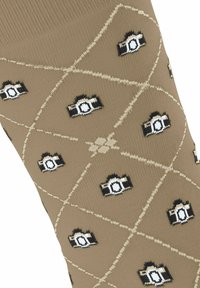 Beżowe skarpetki z wzorem aparatu w czerni i bieli, z diamentowym wzorem w kratkę podkreślonym jasnobrązowym ściegiem.