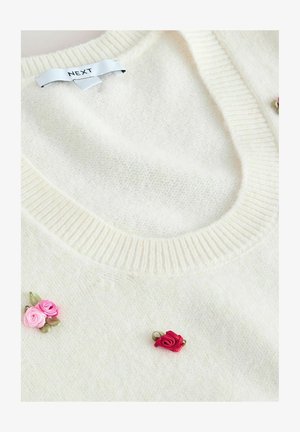 Cream-colored sweater made of soft, textured fabric. Features a ribbed neckline and three embroidered rose accents in pink and red.