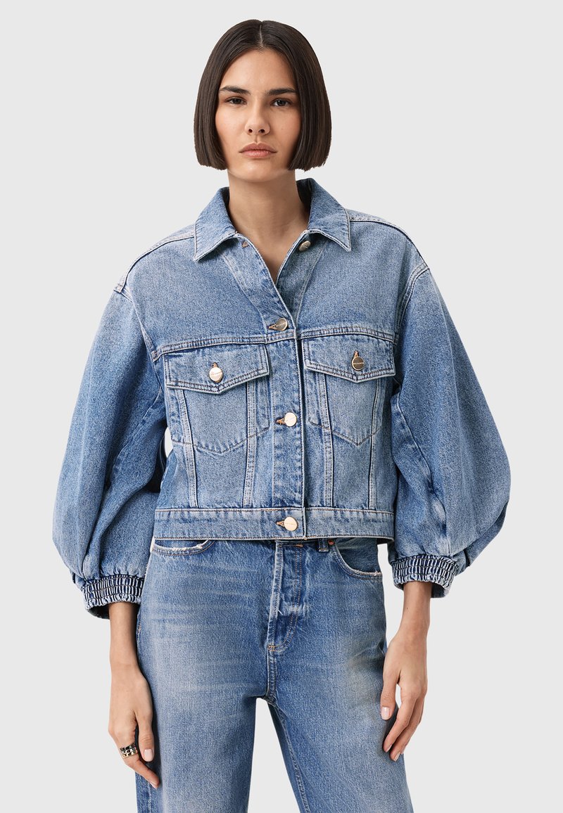 Giacca di jeans con design cropped, colore azzurro chiaro, due tasche sul petto e polsini elasticizzati per un effetto arricciato.