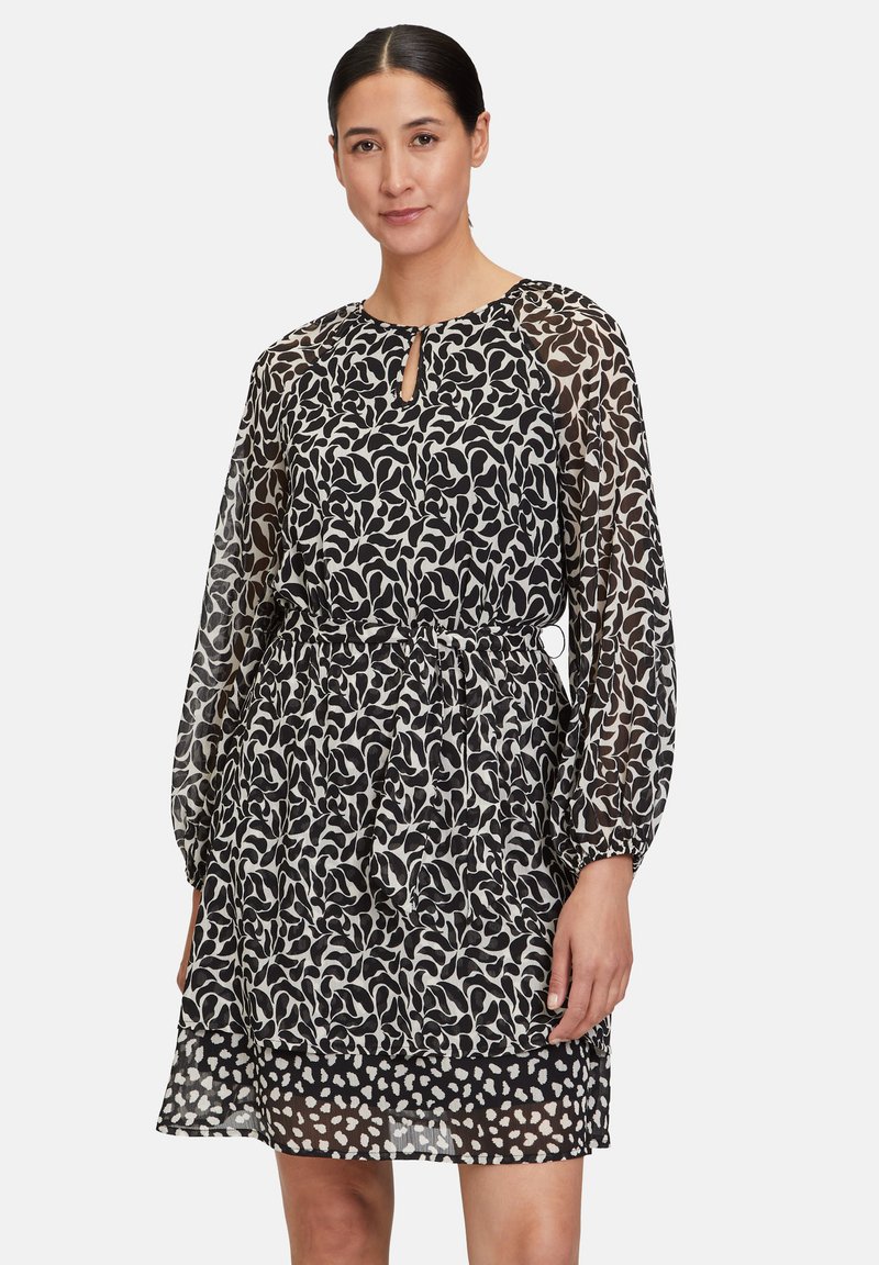 Schwarz-weißer Kleid mit Muster, Keyhole-Ausschnitt, transparenten langen Ärmeln und elastischem Taillenbund. Mehrlagiger, leichter Stoff.