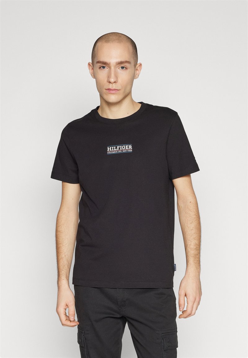T-shirt in cotone nero con un logo "HILFIGER" centrale bianco e blu. Collo a giro classico e maniche corte; vestibilità comoda.