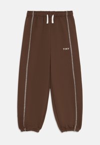 Pantalons de survêtement marron pour enfants avec cordon blanc, surpiqûres contrastées sur les côtés, poignets élastiques et texte "TINY" sur la cuisse gauche.