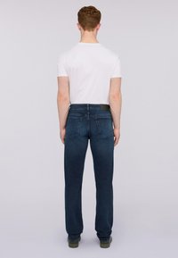 Jeans de color azul oscuro con un diseño de pierna recta, cintura de altura media y dos bolsillos traseros, combinados con una camiseta blanca básica.