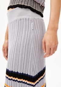 Lichtgrijze geribde gebreide rok met multi-kleurige horizontale strepen. Heeft een strakke tailleband en een label aan de zijkant.