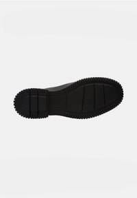 Semelle de chaussure en caoutchouc noir avec des rainures profondes, présentant un profil plat et une surface lisse ; marque en relief près de la zone du talon.