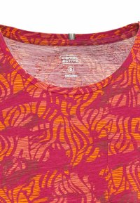 Camiseta de algodón orgánico con cuello redondo, que presenta un vibrante patrón abstracto en tonos rosa y naranja y una textura en toda la prenda.