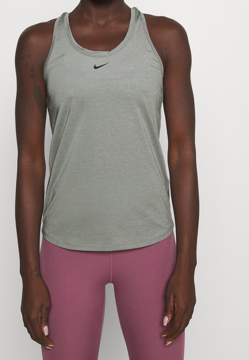 Canottiera sportiva grigia con scollatura rotonda e orlo curvo. Presenta un piccolo logo Nike nero sul petto. Realizzata in tessuto morbido e traspirante.