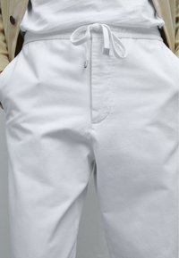 Witte katoenen broek met een relaxed fit. Voorzien van een elastische tailleband met een trekkoord, steekzakken en een gladde textuur.