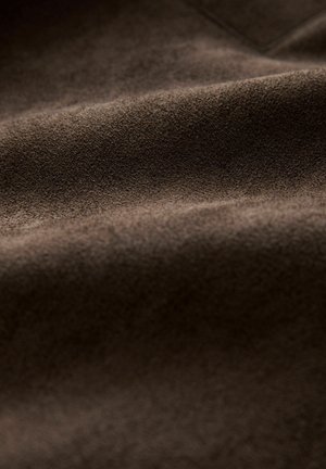 Brown suede fabric with a soft texture, featuring gentle folds and a rich, uniform color, suitable for various textile applications.