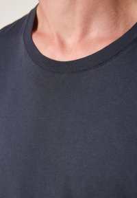 Navy blue crew neck t-shirt made from soft cotton, featuring smooth texture and minimal stitching detail around the neckline.