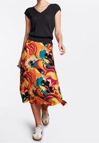 Top negro de manga corta con escote en forma de V, combinado con una falda de largo medio colorida que presenta patrones florales en naranja, amarillo y azul verdoso.
