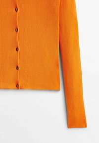 Cardigan à manches longues côtelé orange vif avec des boutons marron sur le devant, présenté à plat sur une surface blanche.