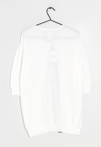 Biały sweter dziany o luźnym kroju, z prążkowanymi rękawami i krawędzią. Wiesza się na czarnym haczyku na jednolitym tle.